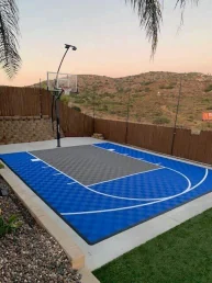 Sports Tiles Buyer’s Guide: Types, Bases, Installation and Cost | My Backyard Sports Fenced backyard half court built with blue and gray sports tiles and a pole-mounted hoop