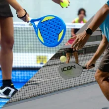 Padel vs pickleball: a blue perforated padel racket and a pickleball paddle held near a net